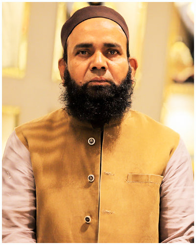 Professional portrait of a man in traditional South Asian dress with beard, warm indoor background