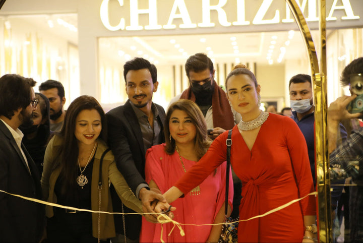 Woman in red dress cutting a ribbon at a Charizma store opening ceremony.