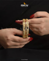 Aurumé Bangles, featuring a unique blend of elegance and modern craftsmanship. Designed with a golden polish, these exquisite kangans are adorned with dazzling diamond-cut stones and delicate stones, exuding a refined charm. The structured pattern and exquisite detailing enhance their luxurious appeal, making this kada an ideal choice for weddings, festive occasions, and special celebrations.