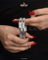 Make a bold statement with these intricately designed Azurielle Bangles, featuring a unique blend of elegance and modern craftsmanship. Adorned with dazzling diamond-cut stones and delicate blue accents, they exude a refined charm. The structured pattern and exquisite detailing enhance their luxurious appeal, making them an ideal choice for weddings, festive occasions, and special celebrations.