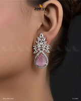 The Ivy Earrings showcase a mesmerizing combination of elegance and luxury, featuring dazzling crystal glass stones framed with sparkling American-cut diamond stones. These statement earrings boast a refined drop design with intricate detailing and a high-quality rhodium polish, adding a touch of sophistication to any outfit. Perfect for weddings, evening parties, and festive occasions.