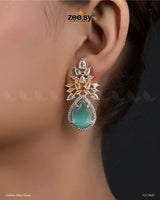 The Ivy Earrings showcase a mesmerizing combination of elegance and luxury, featuring dazzling crystal glass stones framed with sparkling American-cut diamond stones. These statement earrings boast a refined drop design with intricate detailing and a high-quality rhodium polish, adding a touch of sophistication to any outfit. Perfect for weddings, evening parties, and festive occasions.