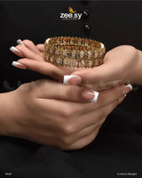 Lonicera Bangles, available in Golden and Multi variants. These exquisite kangans are embellished with dazzling diamond-cut stones and crystal glass stones, adding a touch of brilliance. The Golden version exudes timeless elegance, while the Multi variant brings a vibrant charm, this is a stunning addition to any grand occasions.