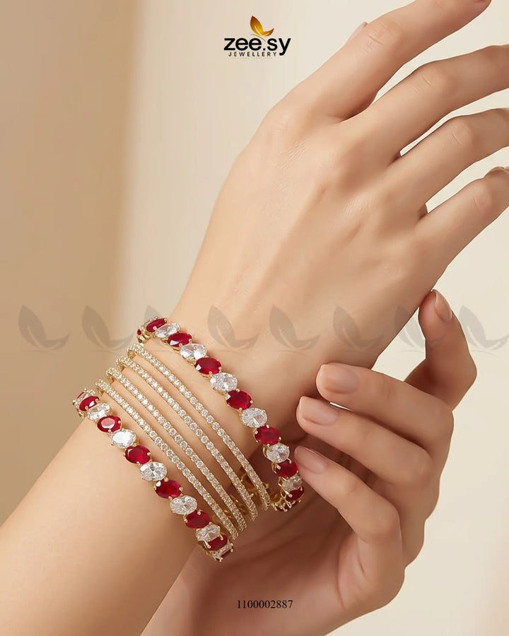 Red oval gemstone paved bangles by AJ03, elegant gold-tone jewelry with sparkling gemstone accents, worn as stylish accessories.