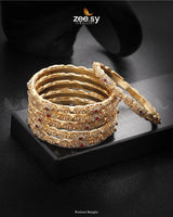 Rudrani Bangles showcase exquisite craftsmanship with intricate patterns and shimmering stone embellishments. The rhodium-polished accents enhance their elegance, making them a timeless addition to any jewelry collection. Perfect for weddings and festive occasions, these bangles complement traditional and bridal attire beautifully.