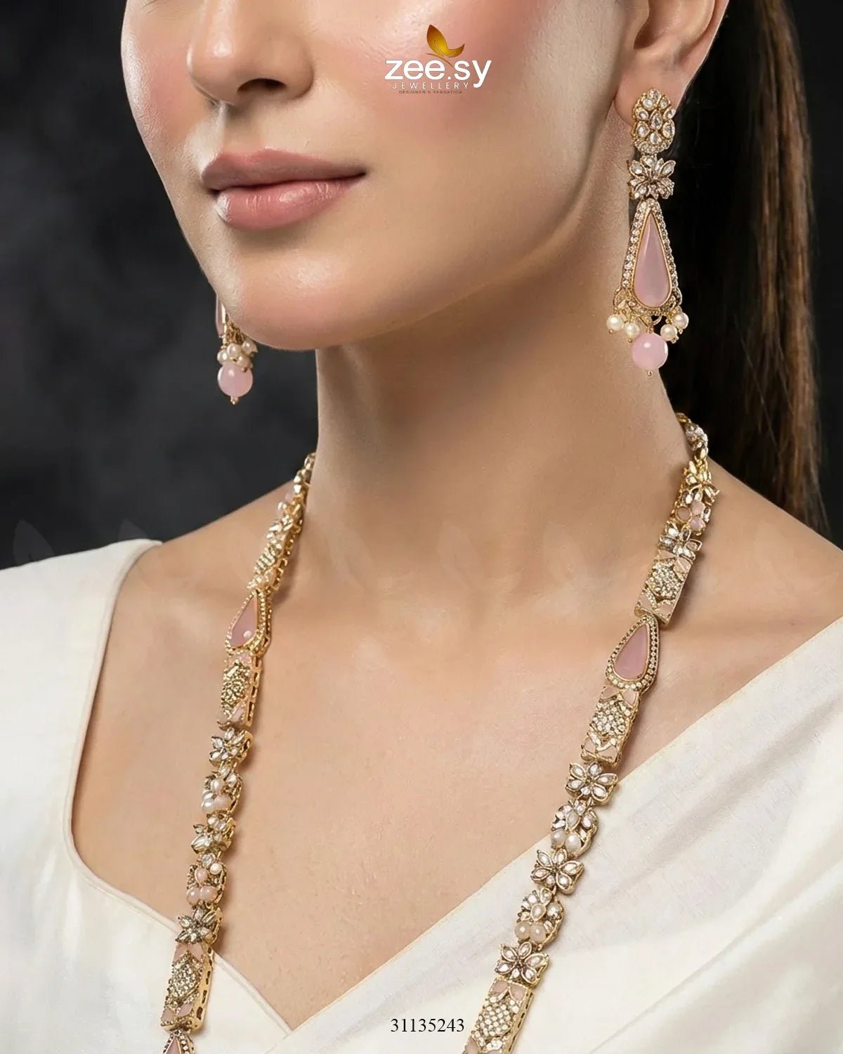 Close-up of a woman wearing a gold necklace and earrings with pink stones, branded 'zee sy'.