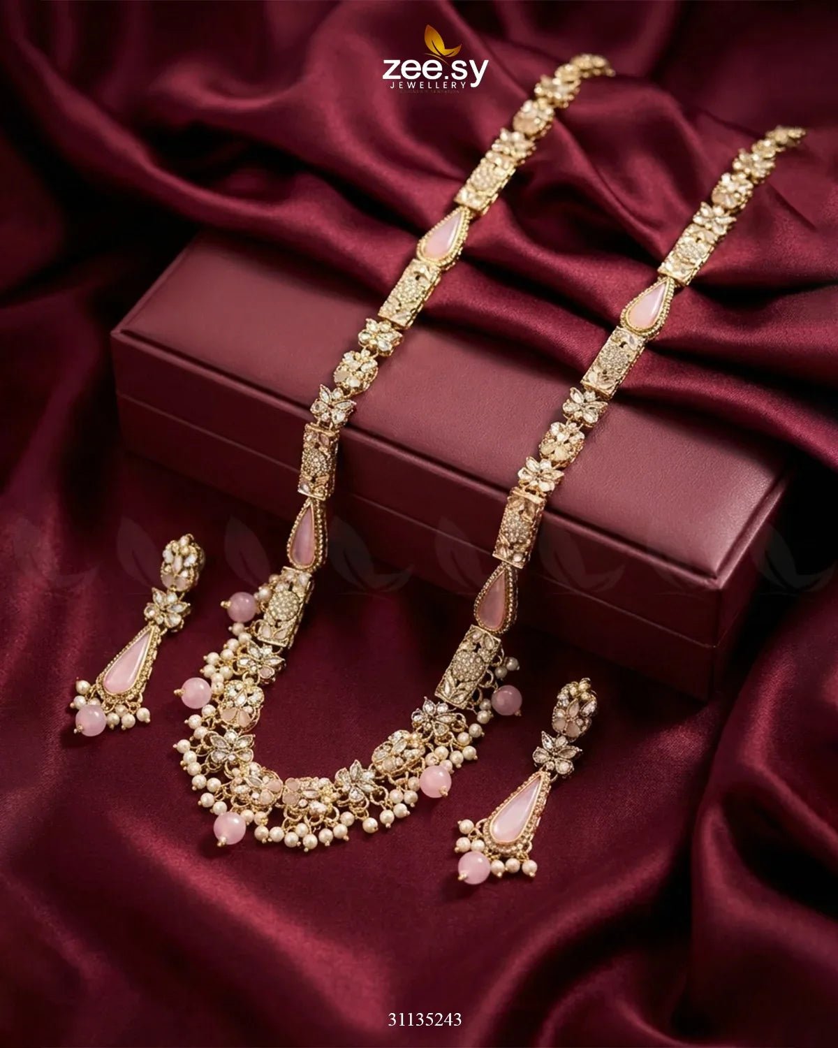 Gold necklace and earrings set on a maroon fabric background with 'zee sy' branding.