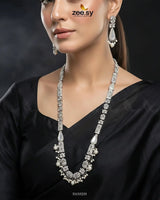 Woman wearing a silver necklace and earrings with 'zeesy' branding.