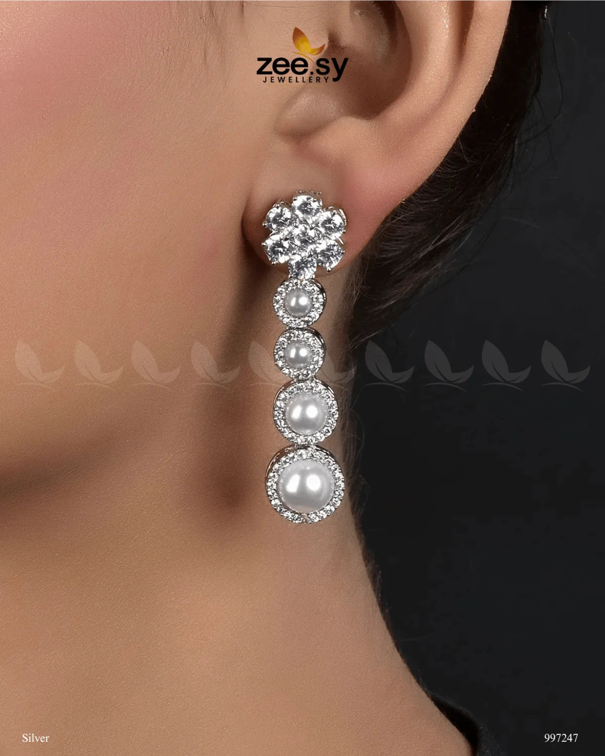 Vyom Earrings embody elegance and sophistication with their luxurious design. Featuring a dazzling arrangement of&nbsp;American-cut diamond stones, Vintage Pearl Earrings are adorned with luminous pearls in a cascading pattern, creating a graceful and timeless look. The refined setting is complemented by a golden or silver polish, adding a radiant finish that enhances their beauty.